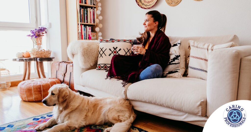 A woman relaxes with her dog while sipping on tea, representing how self-care can combat caregiver stress.