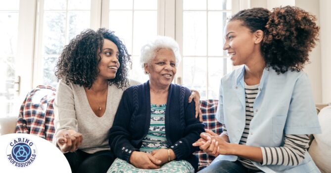 A caregiver talks with a client and her daughter, representing the type of communication that is vital when taking on a person-centered care approach.