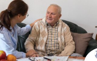 A caregiver compassionately listens to an older man, representing the kind of patience and empathy that help with communicating with clients who have dementia.