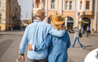 2 older adults hug while on vacation representing the successful outing that can still happen while caring for elderly loved ones.