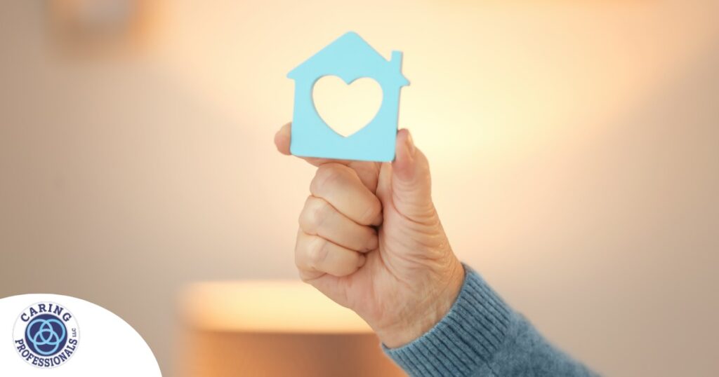 A hand holds up a cutout of a home with a heart in it, representing the home care industry.