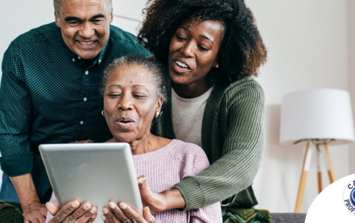 A daughter looks at a tablet with her older parents, representing technology and how ti can help with aging in place.